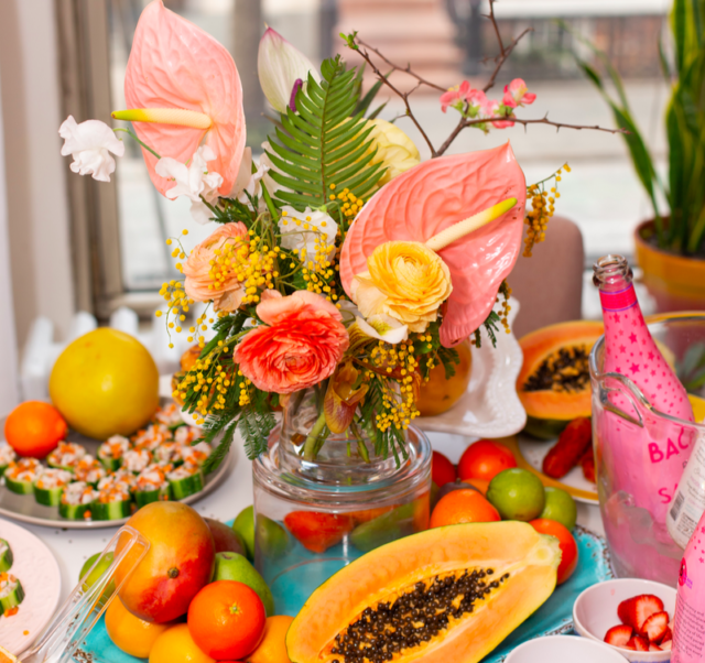 Galentine's Day Brunch decorated dining room table filled with fruit; there are two bottles of Bacana Sangria