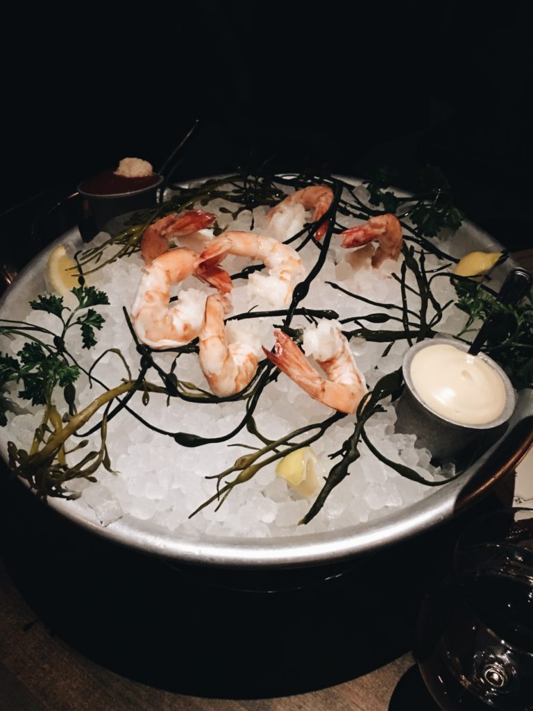 shrimp cocktail served in metal bowl with crushed ice inside and condiments