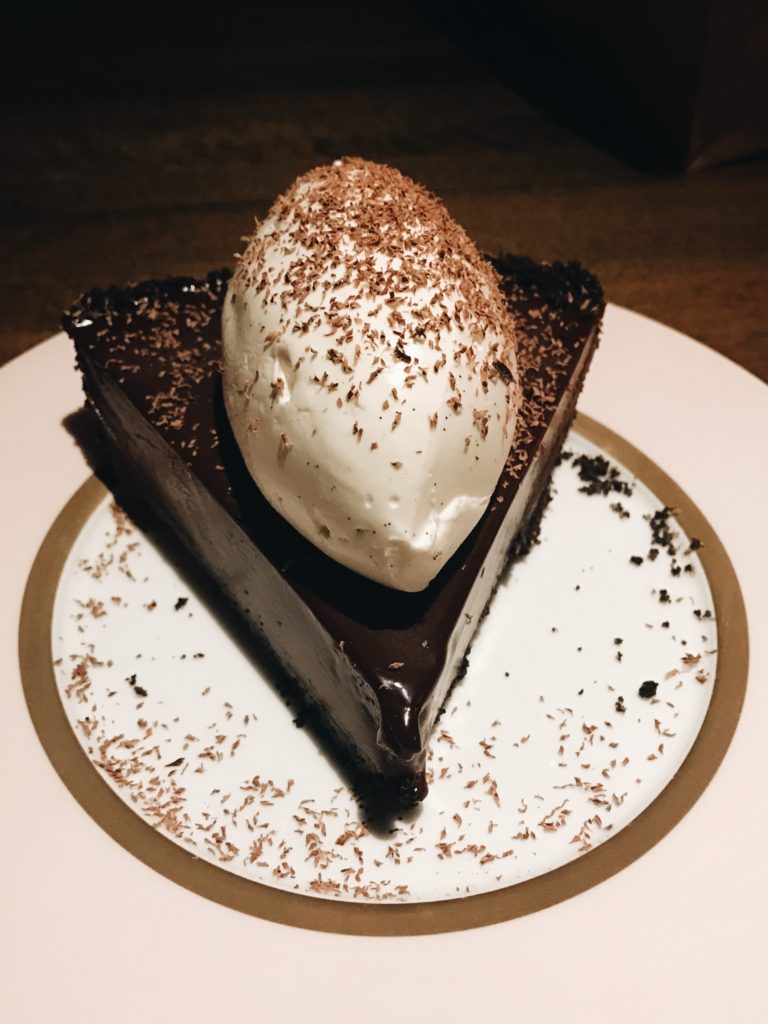 chocolate fudge cake slice topped with vanilla icecream and nut shavings