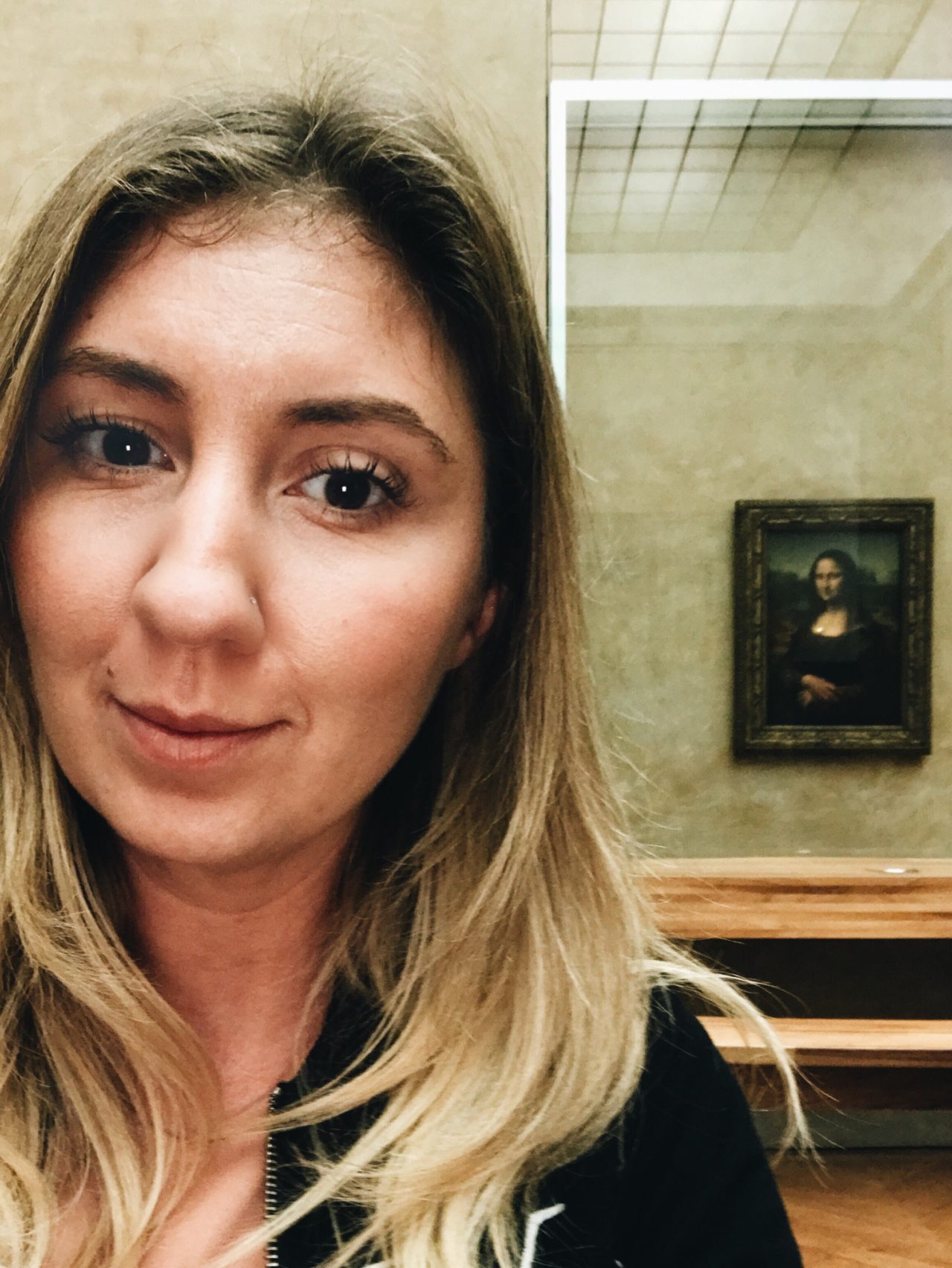 Monica in a selfie photo with the Mona Lisa at The Louvre in paris
