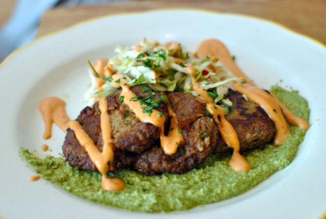 a kitchen mouse plate with black bean and rice patties topped with a peach-colored sauce and plant garnishings